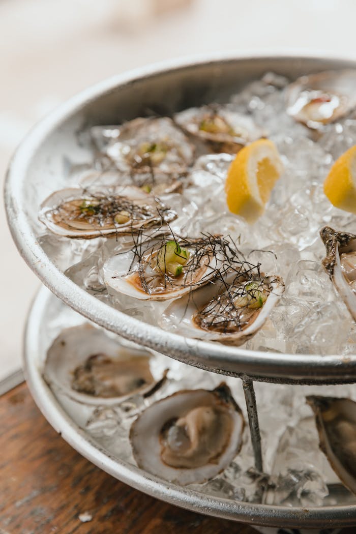 Services Chilled oysters garnished with lemon wedges served on a bed of ice, perfect for seafood lovers.