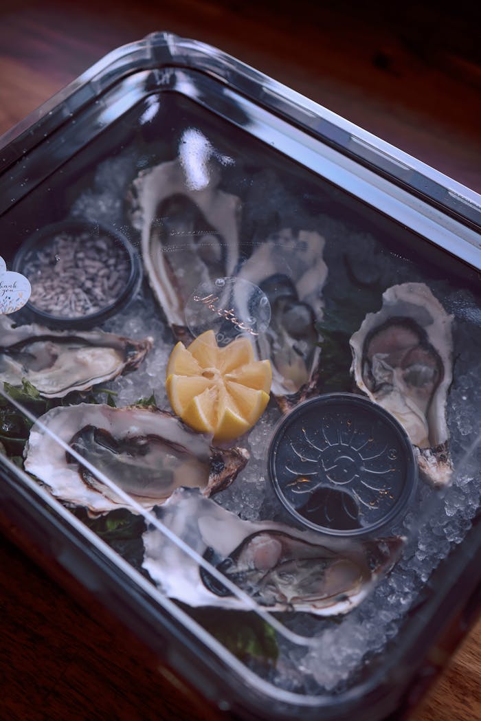 About A seafood delicacy featuring fresh oysters on ice with a lemon slice, perfect for gourmet dining.