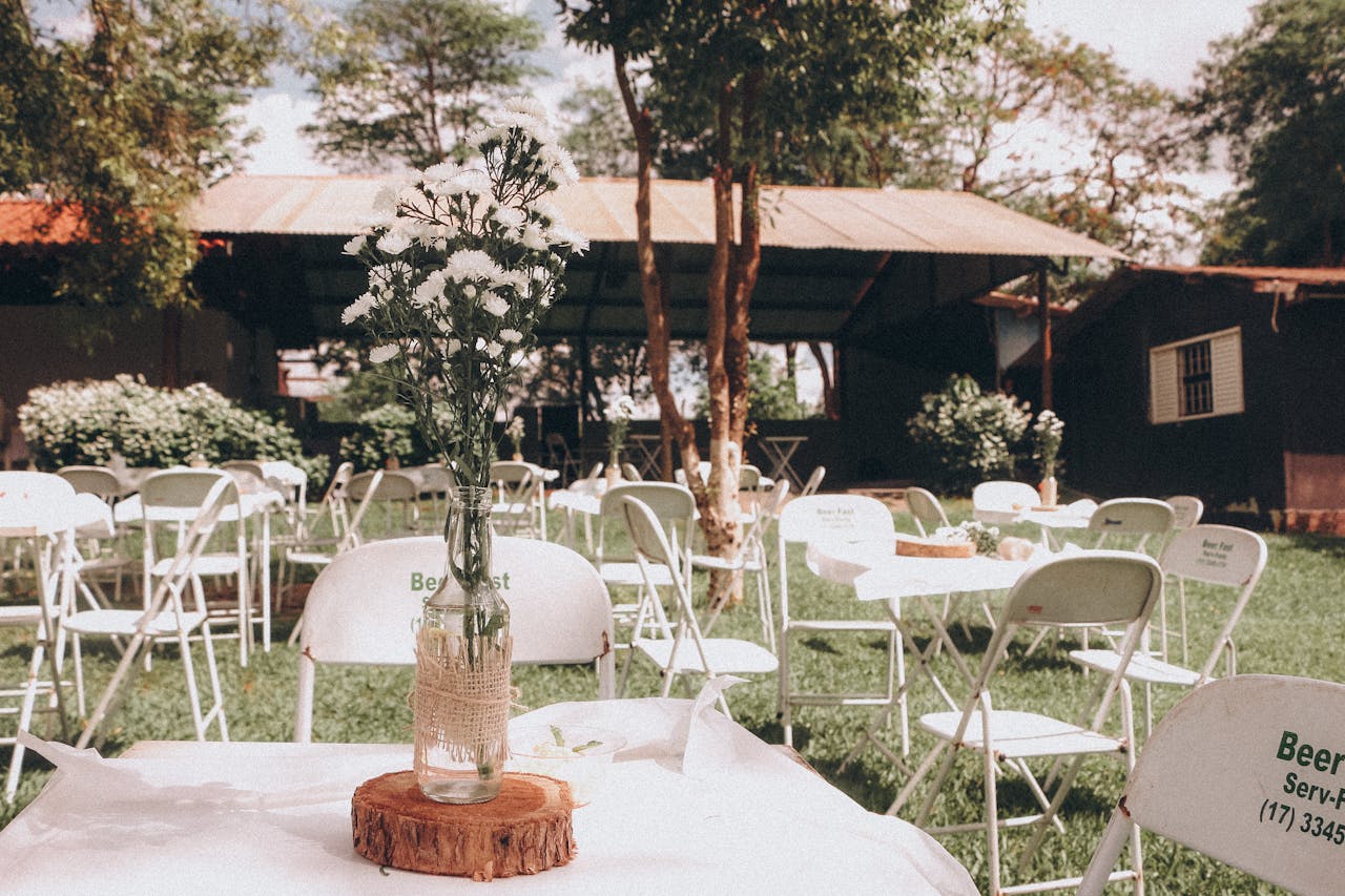 Services Charming outdoor garden event setup with floral centerpiece on a sunny day.