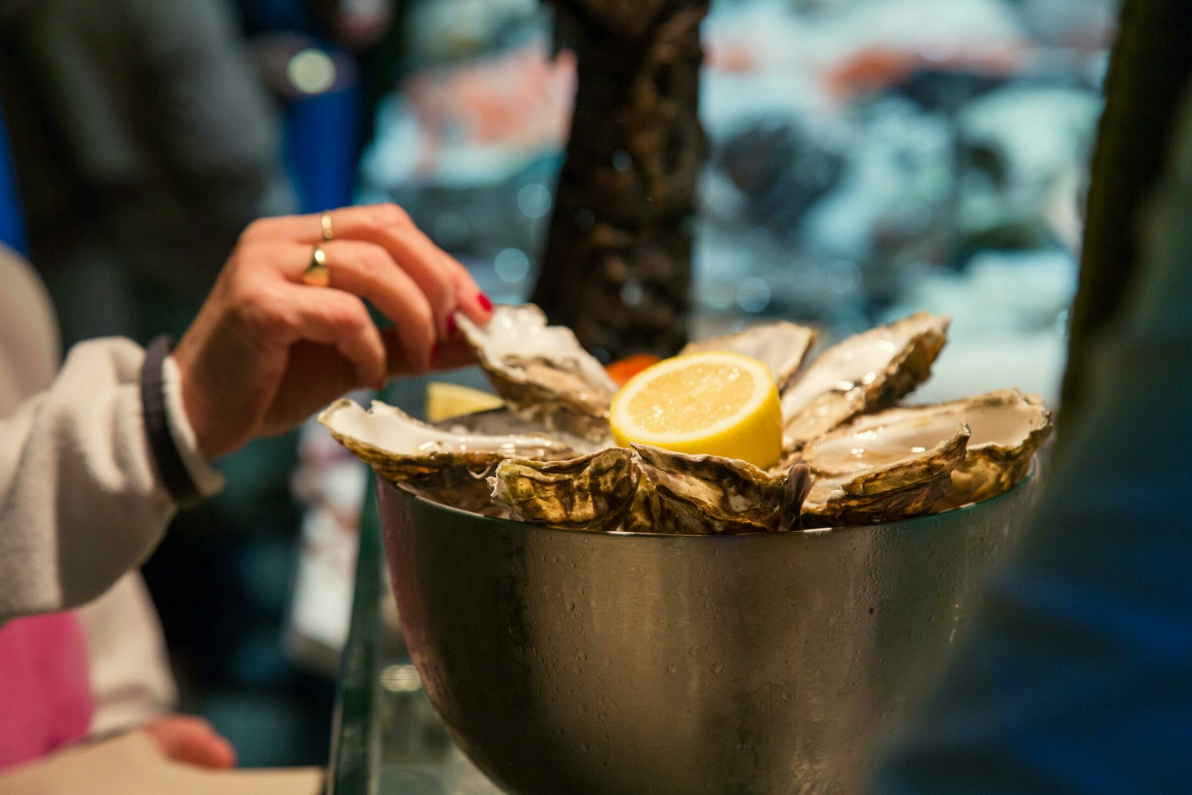 Bar à Huîtres Hand reaches for fresh oysters with lemon at an Irish seafood restaurant.